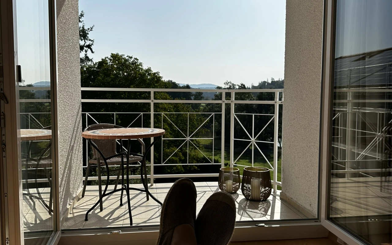 Bild Balkon eines Patientenzimmers mit Sitzgelegenheit und Blick ins Grüne.